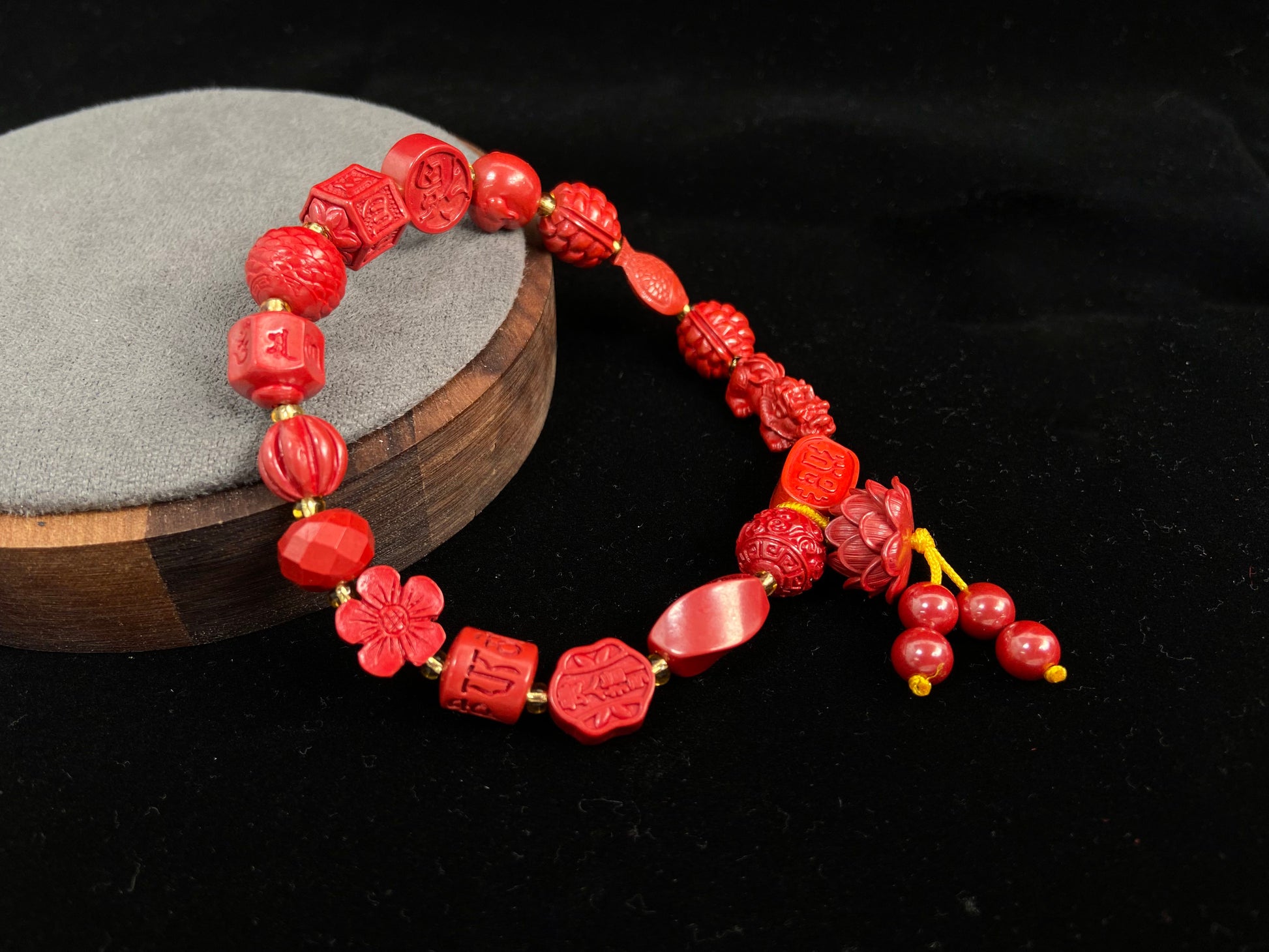 This cinnabar bracelet showcases an array of symbolic beads in pumpkin, peach blossom, fortune, and fish shapes, complete with a lotus charm and four rotating beads.