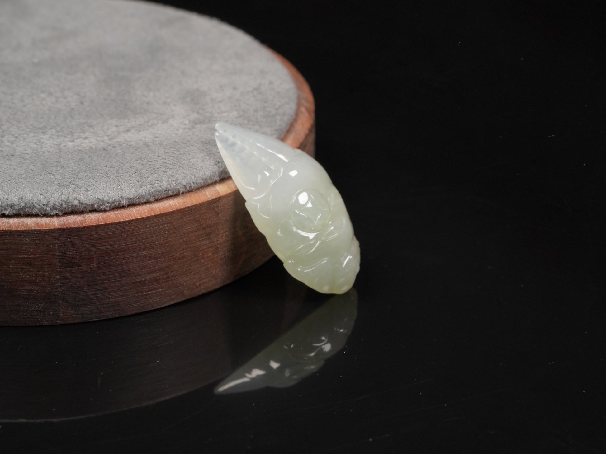 A crab-claw shaped jadeite piece with a milky white base and a subtle wash of pale green.