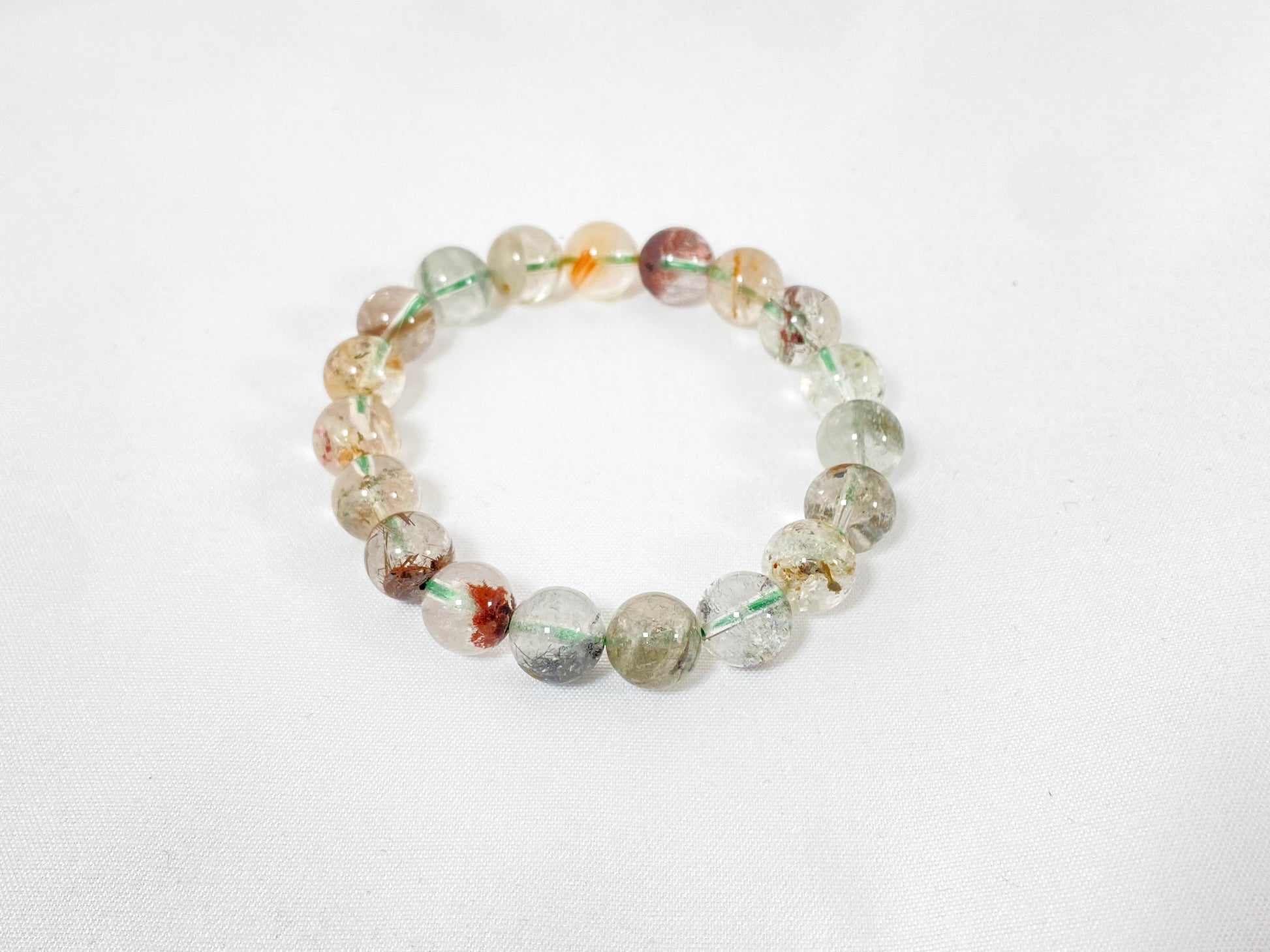 A phantom quartz bracelet showcasing white, red, golden, and pink inclusions.