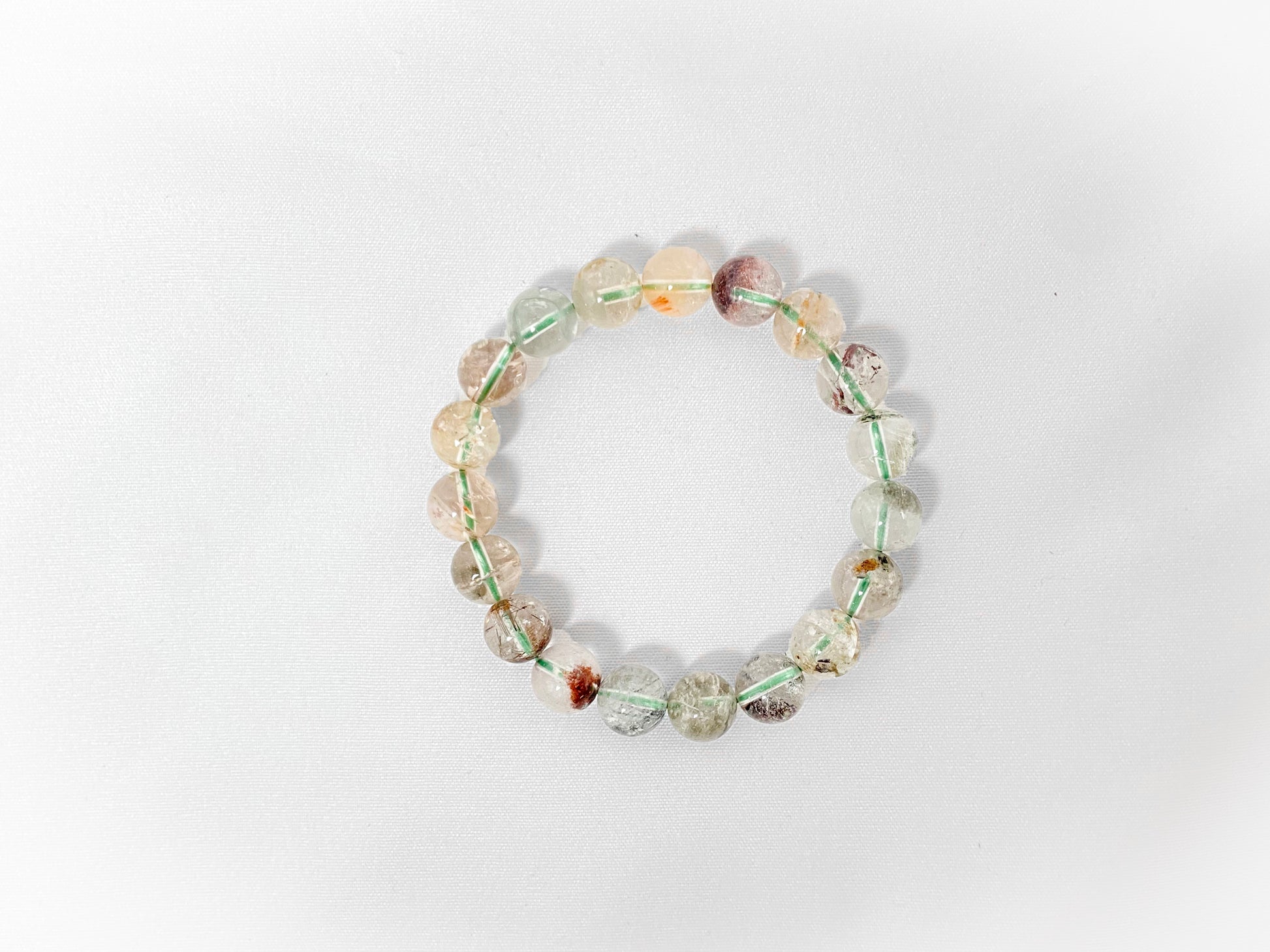 A phantom quartz bracelet showcasing white, red, golden, and pink inclusions.