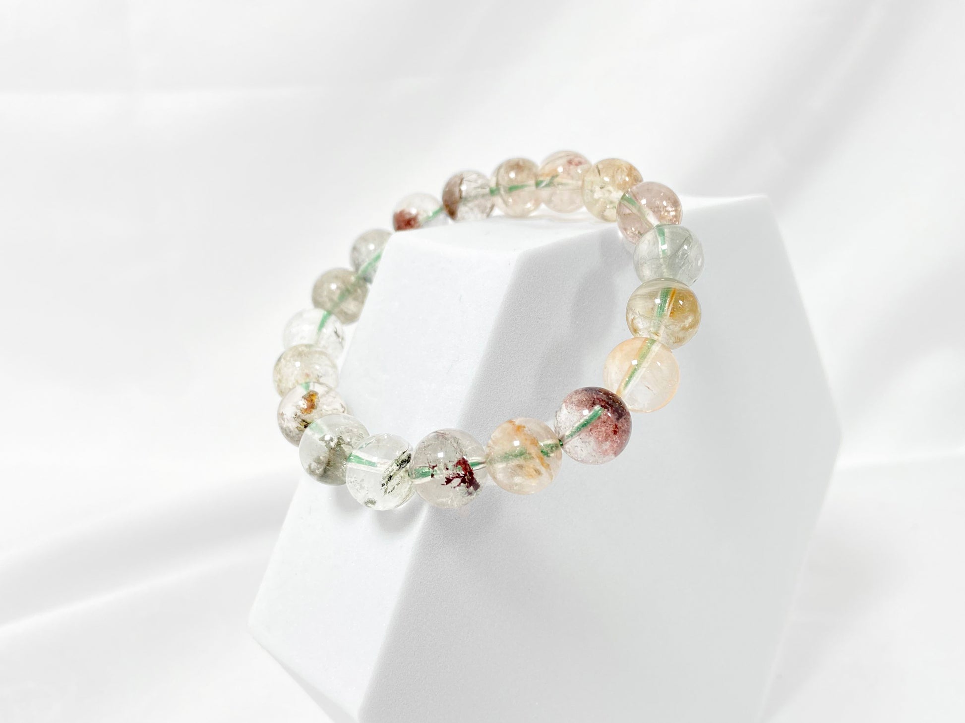 A phantom quartz bracelet showcasing white, red, golden, and pink inclusions.