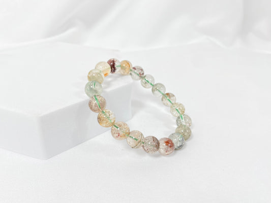 A phantom quartz bracelet showcasing white, red, golden, and pink inclusions.