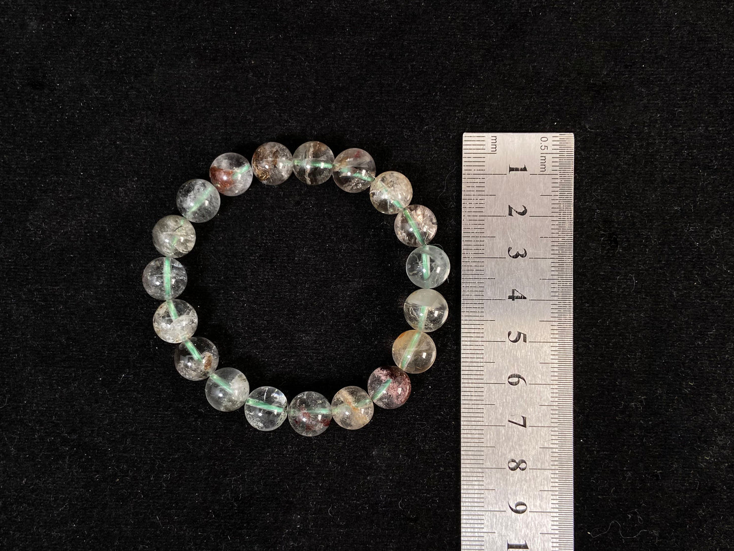 A phantom quartz bracelet showcasing white, red, golden, and pink inclusions.