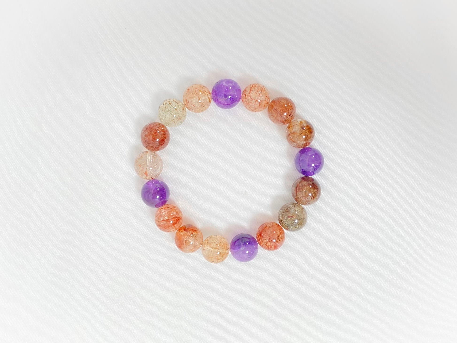 Super 7 crystal beads, a natural inclusion stone with hair-like, flaky, and speckled patterns in vibrant purple, red, orange, and black.