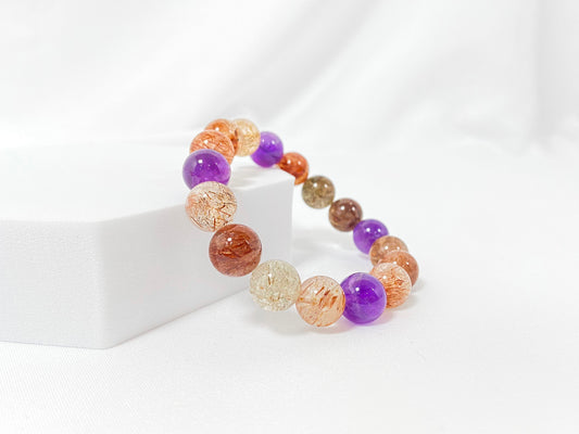 Super 7 crystal beads, a natural inclusion stone with hair-like, flaky, and speckled patterns in vibrant purple, red, orange, and black.