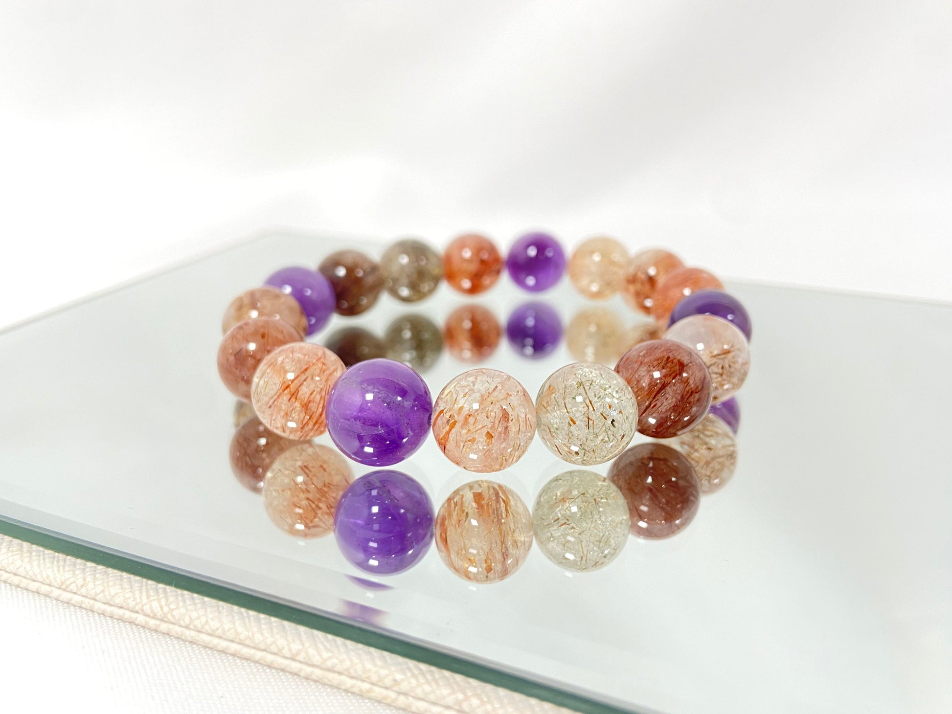 Super 7 crystal beads, a natural inclusion stone with hair-like, flaky, and speckled patterns in vibrant purple, red, orange, and black.