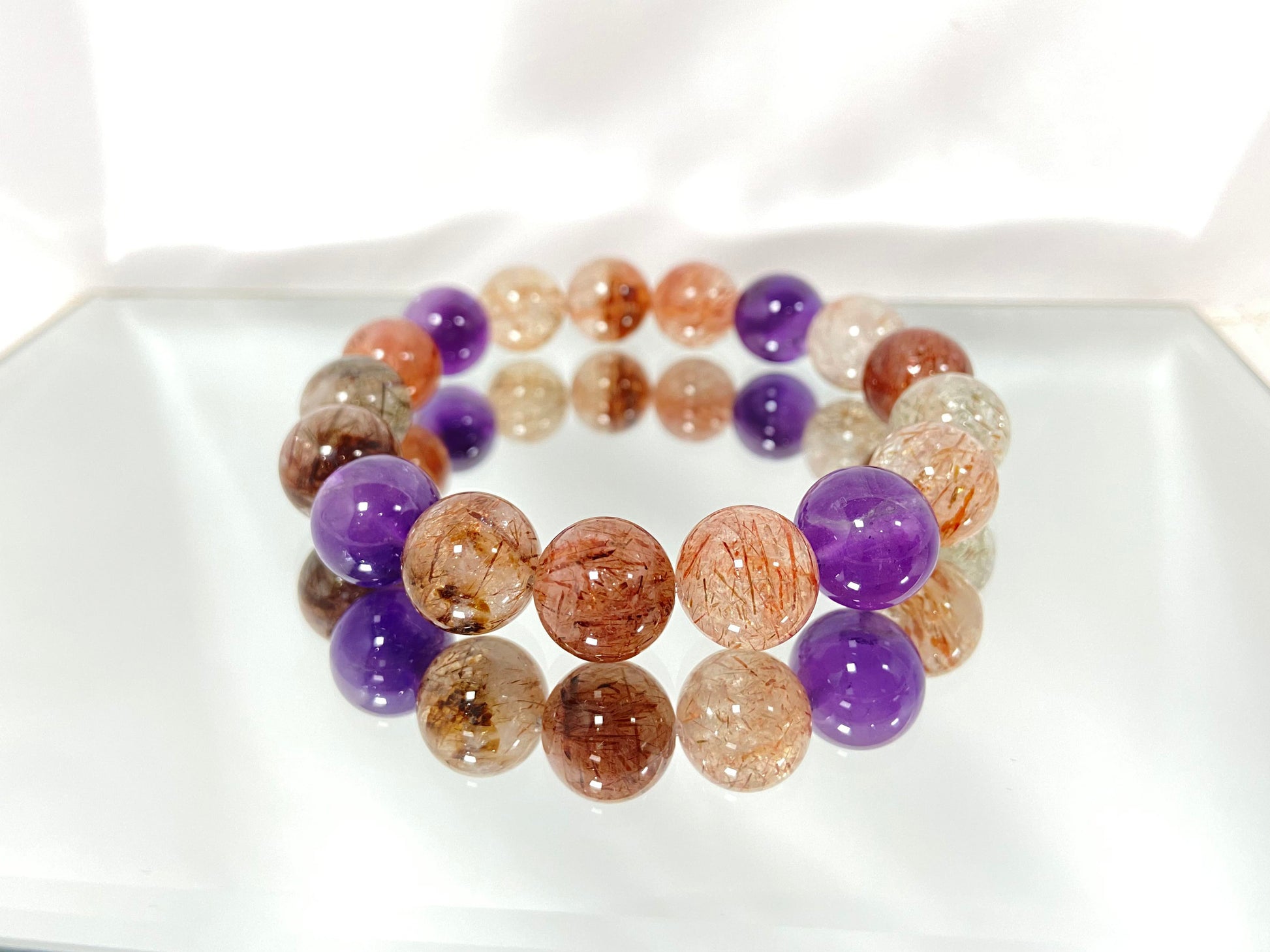 Super 7 crystal beads, a natural inclusion stone with hair-like, flaky, and speckled patterns in vibrant purple, red, orange, and black.