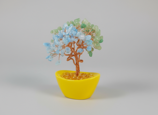 Decorative tree with blue and green leaves in a yellow pot on a white background