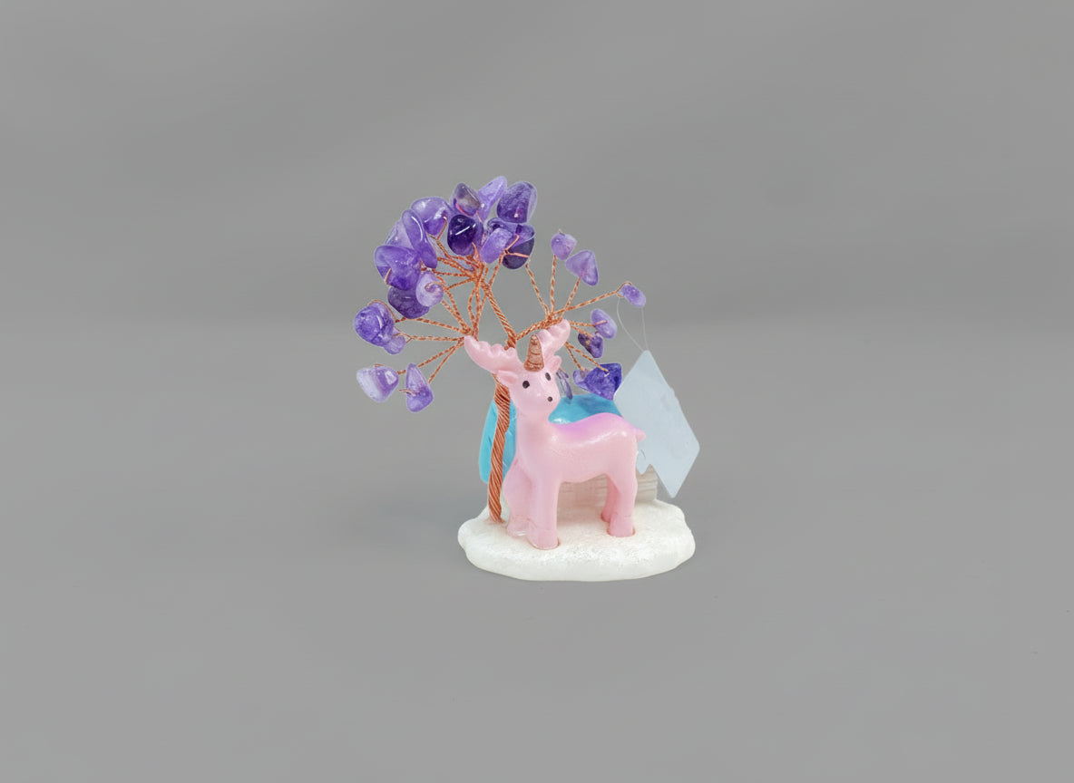 An amethyst crystal tree accompanied by a pink deer and a white cottage with a blue roof.