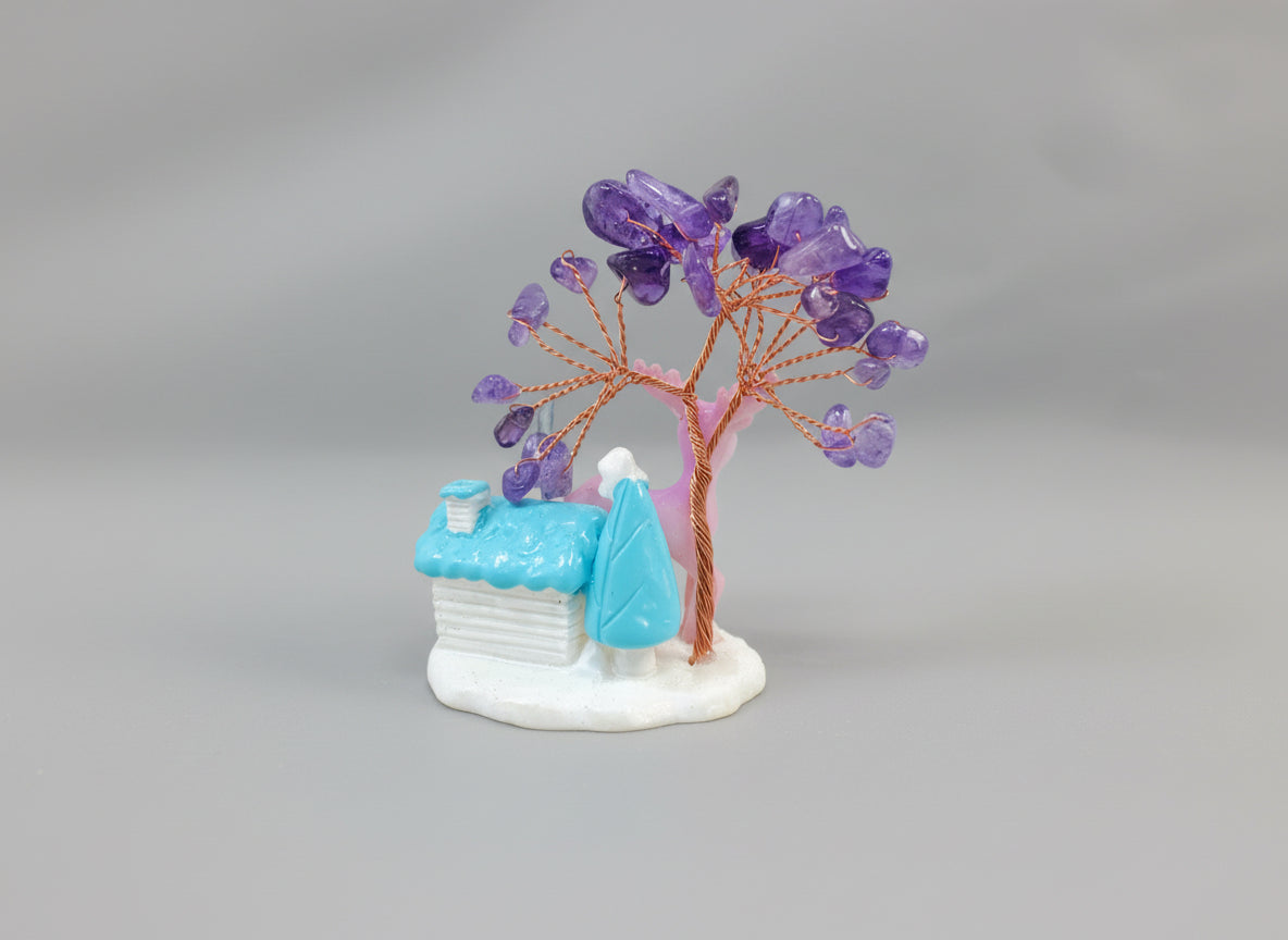 An amethyst crystal tree accompanied by a pink deer and a white cottage with a blue roof.