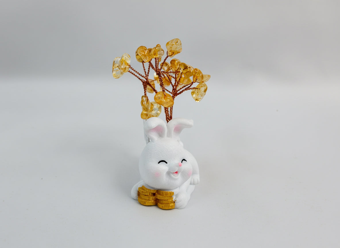 A citrine tree is set on a white rabbit holding several coins.