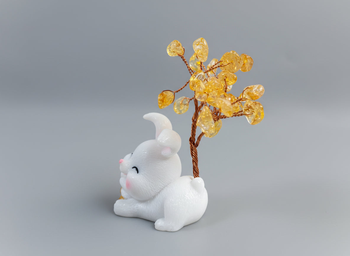 A citrine tree is set on a white rabbit holding several coins.