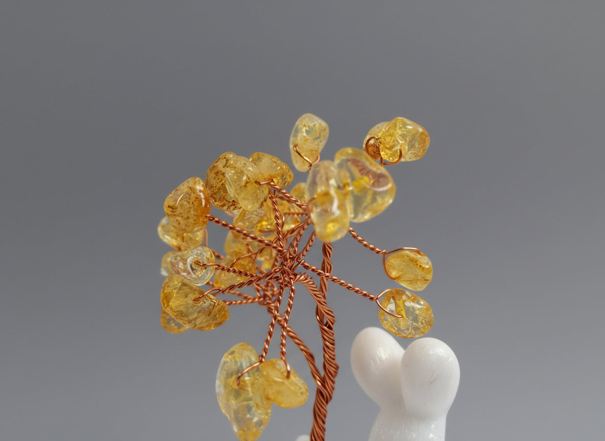 A citrine tree is set on a white rabbit holding several coins.