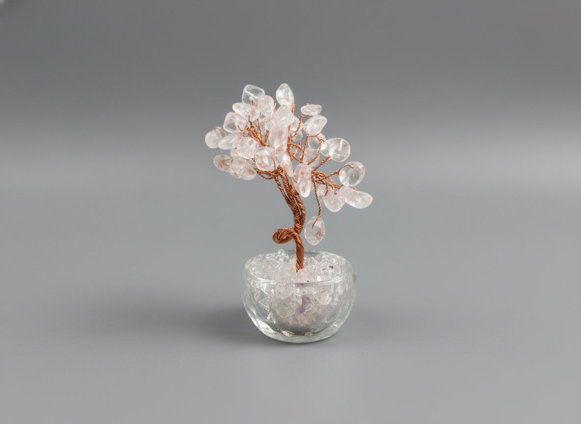 A rose quartz crystal tree in a clear glass pot.