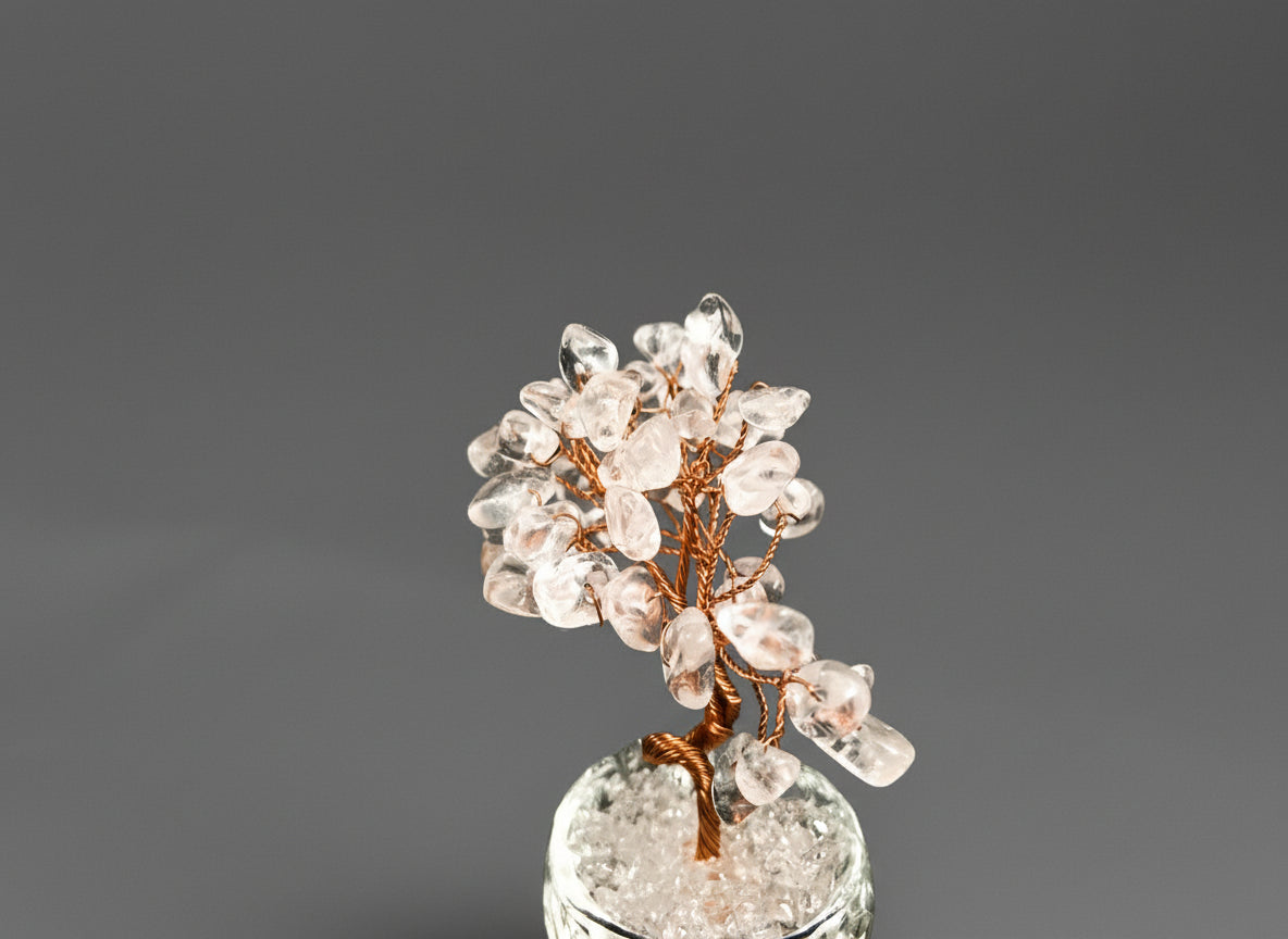A rose quartz crystal tree in a clear glass pot.