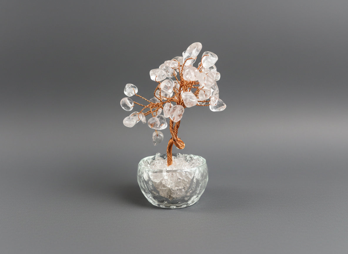 A rose quartz crystal tree in a clear glass pot.