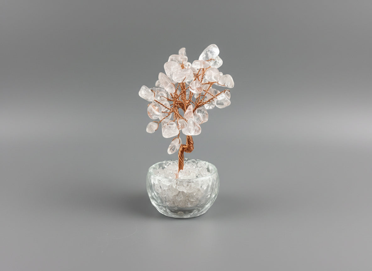A rose quartz crystal tree in a clear glass pot.