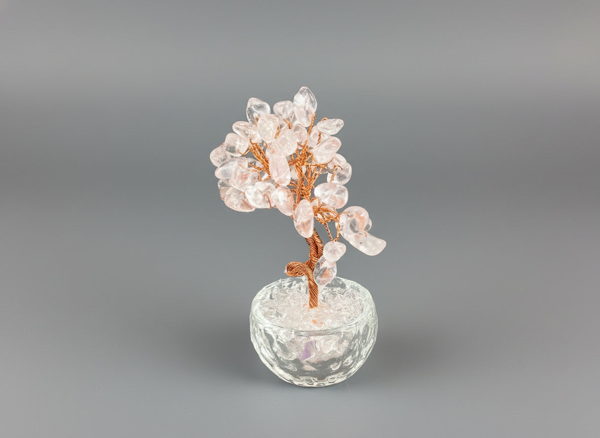 A rose quartz crystal tree in a clear glass pot.