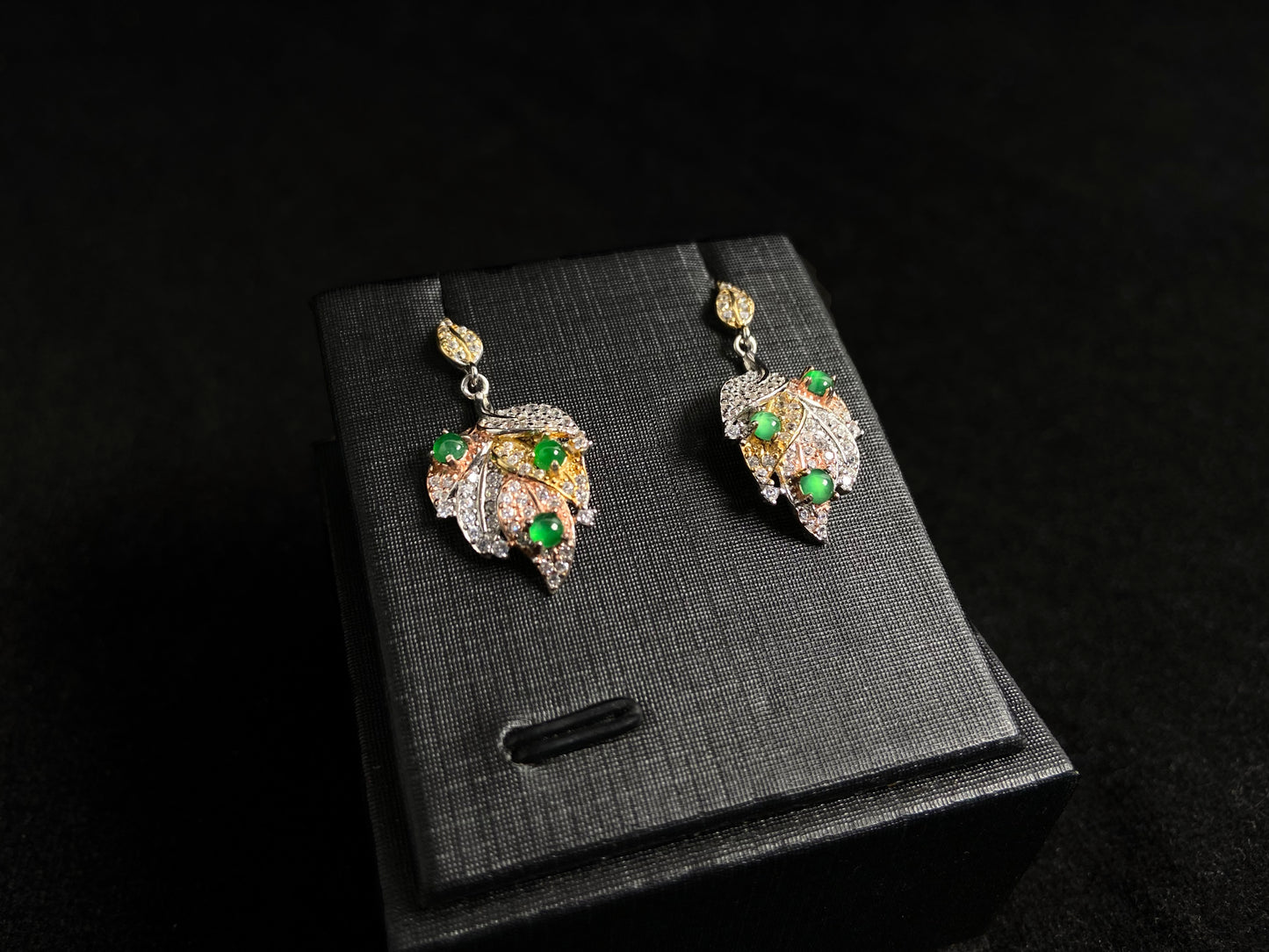 A pair of earrings featuring two 925 silver leaves, each adorned with three green jade beads, available in gold plated or natural silver finish.