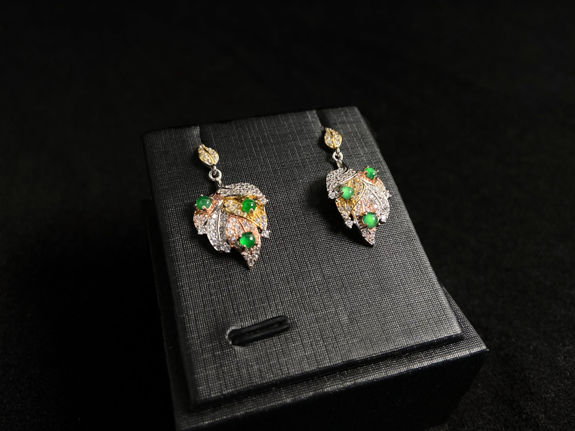 A pair of earrings featuring two 925 silver leaves, each adorned with three green jade beads, available in gold plated or natural silver finish.