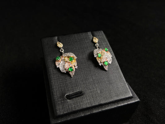 A pair of earrings featuring two 925 silver leaves, each adorned with three green jade beads, available in gold plated or natural silver finish.