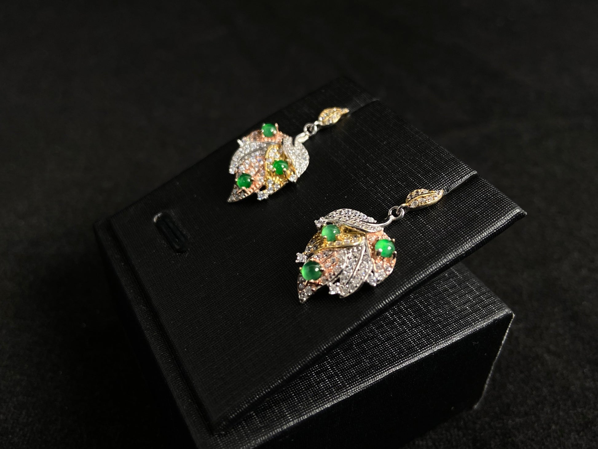 A pair of earrings featuring two 925 silver leaves, each adorned with three green jade beads, available in gold plated or natural silver finish.