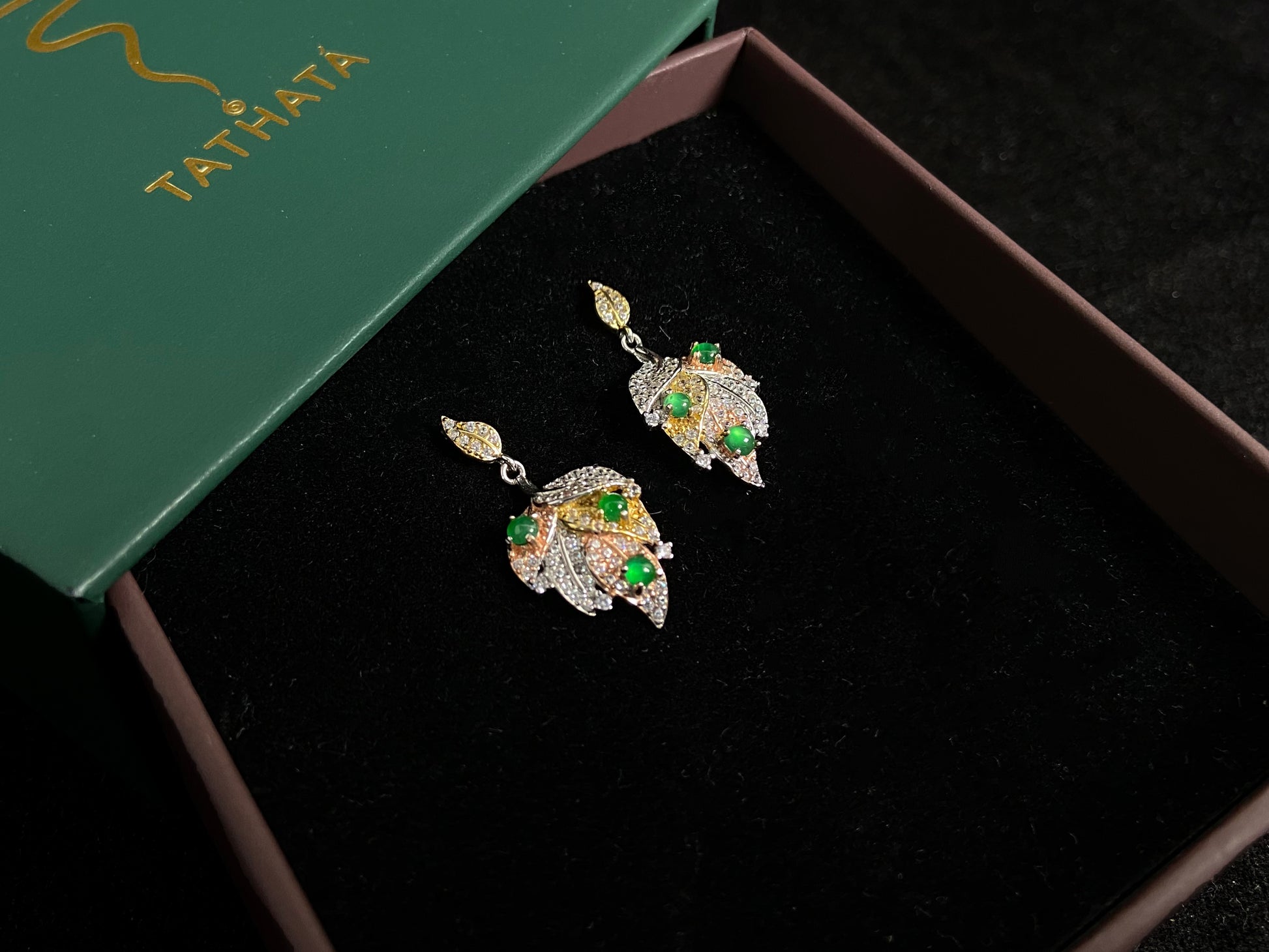 A pair of earrings featuring two 925 silver leaves, each adorned with three green jade beads, available in gold plated or natural silver finish.