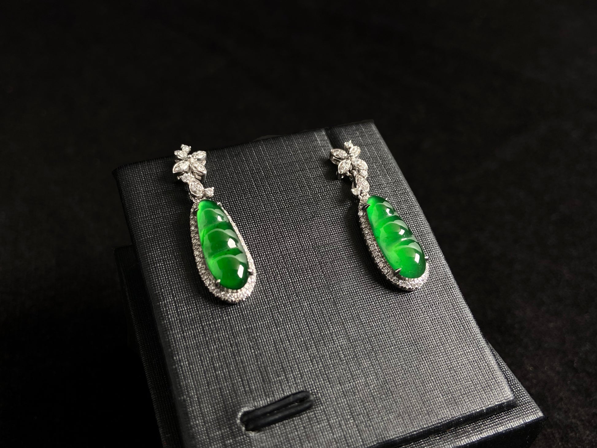 These elegant earrings feature imperial green jadeite lucky beans, each meticulously set in 18K gold with secure prong settings.