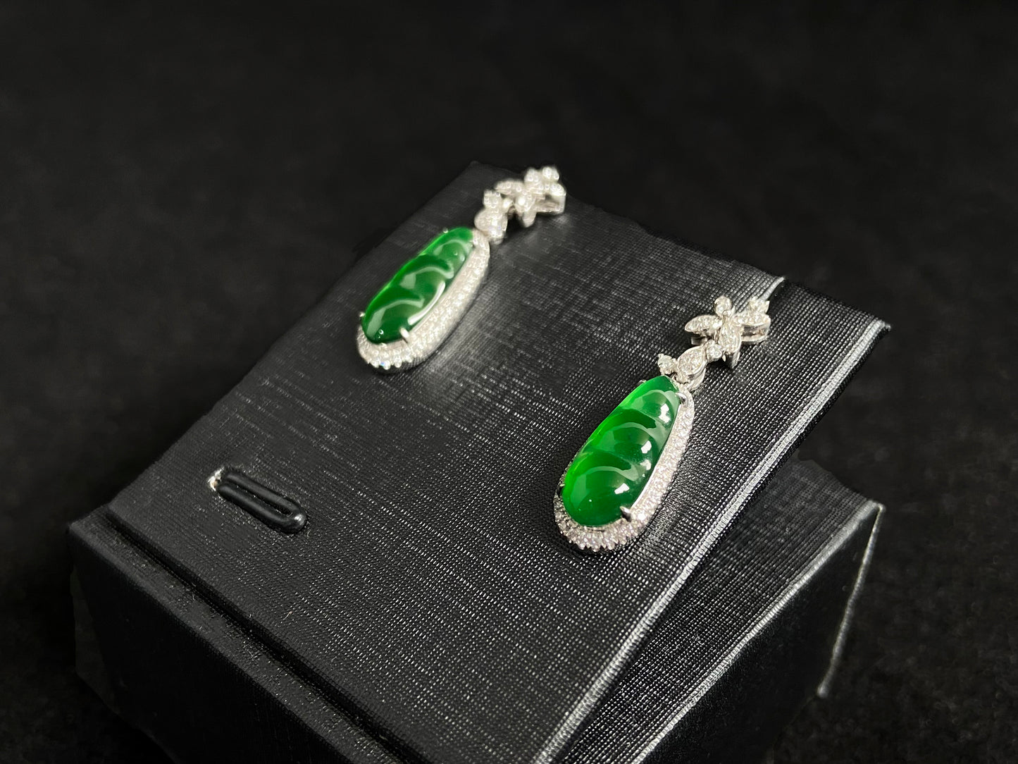 These elegant earrings feature imperial green jadeite lucky beans, each meticulously set in 18K gold with secure prong settings.