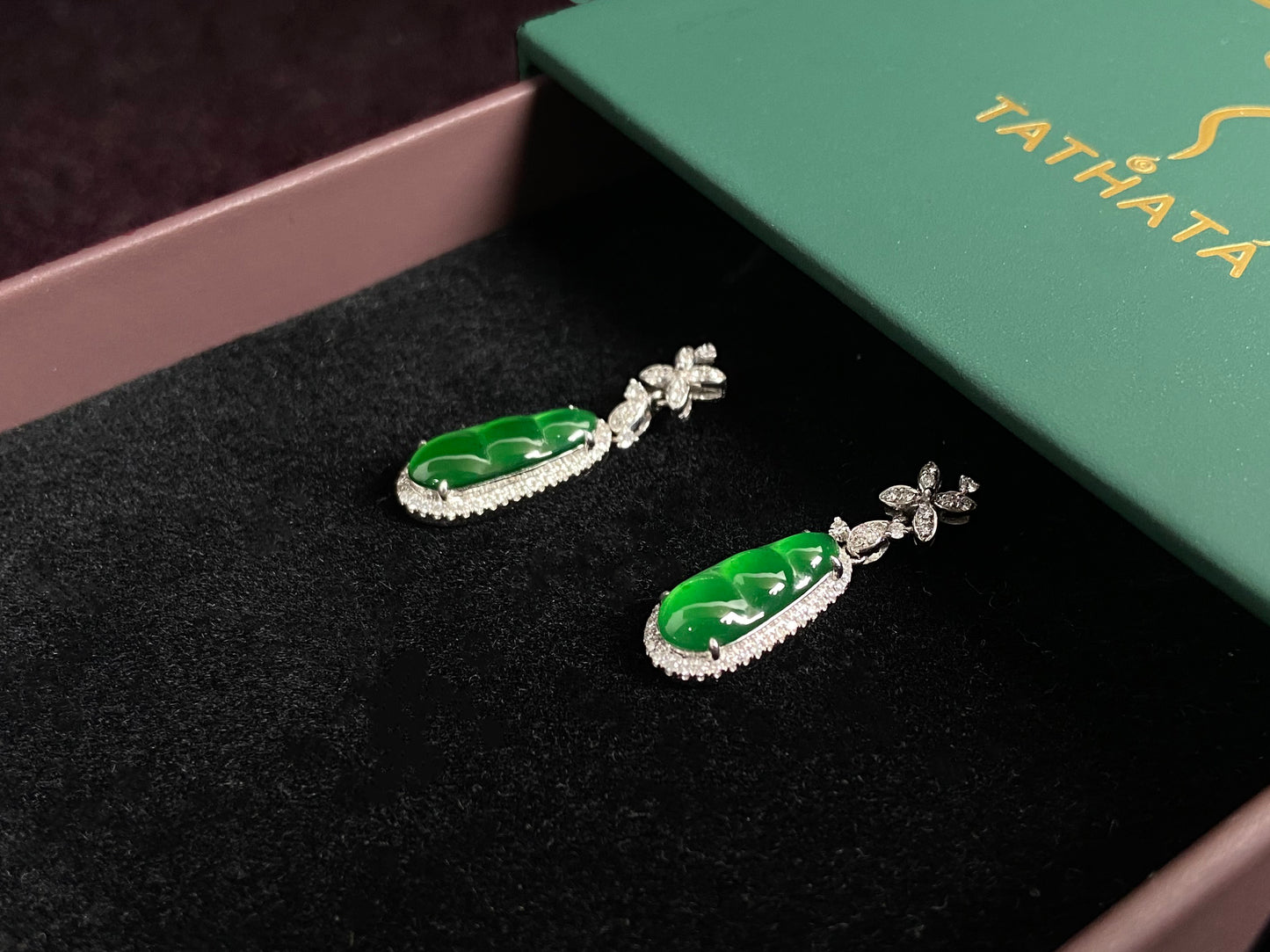 These elegant earrings feature imperial green jadeite lucky beans, each meticulously set in 18K gold with secure prong settings.