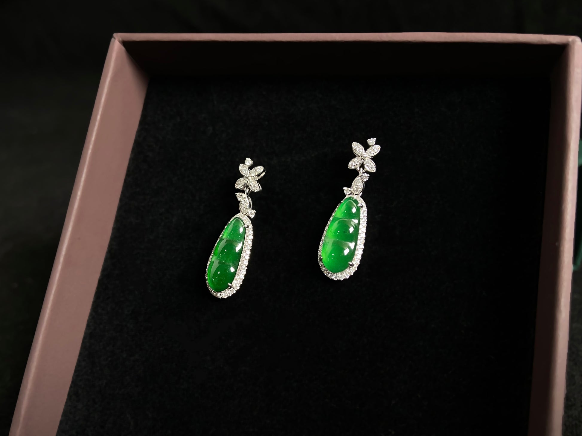 These elegant earrings feature imperial green jadeite lucky beans, each meticulously set in 18K gold with secure prong settings.