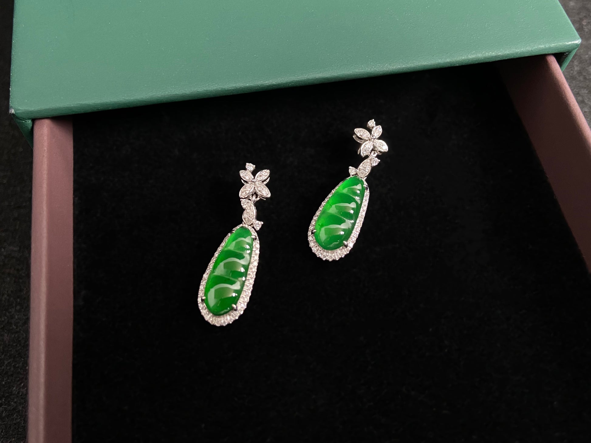 These elegant earrings feature imperial green jadeite lucky beans, each meticulously set in 18K gold with secure prong settings.