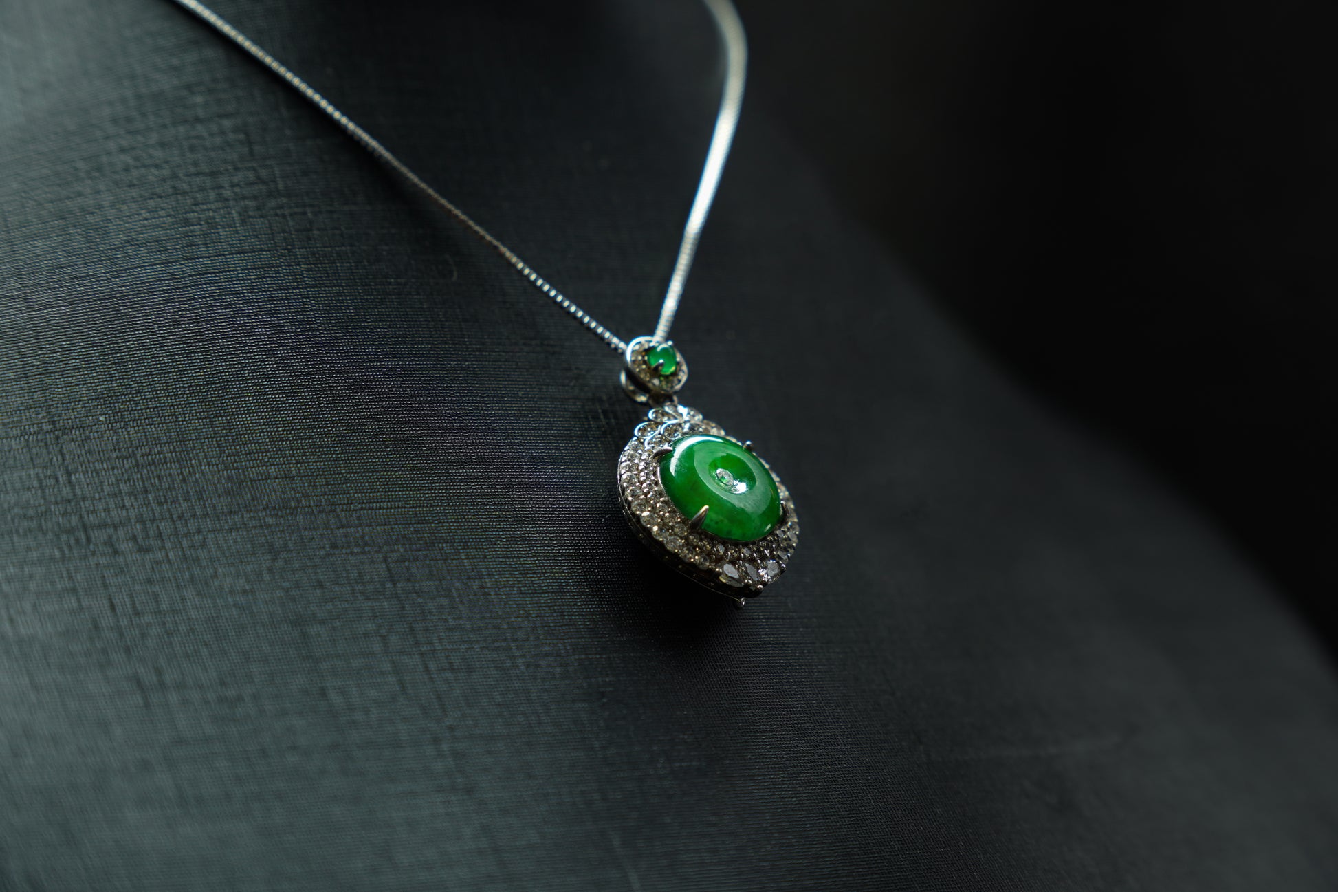 Green gemstone necklace on a dark fabric background