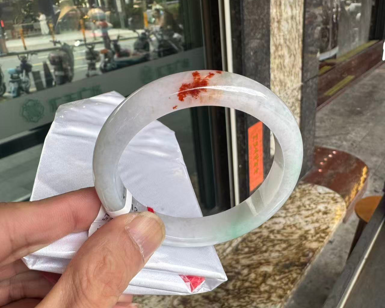 A white and green jade bangle with brownish yellow accents.