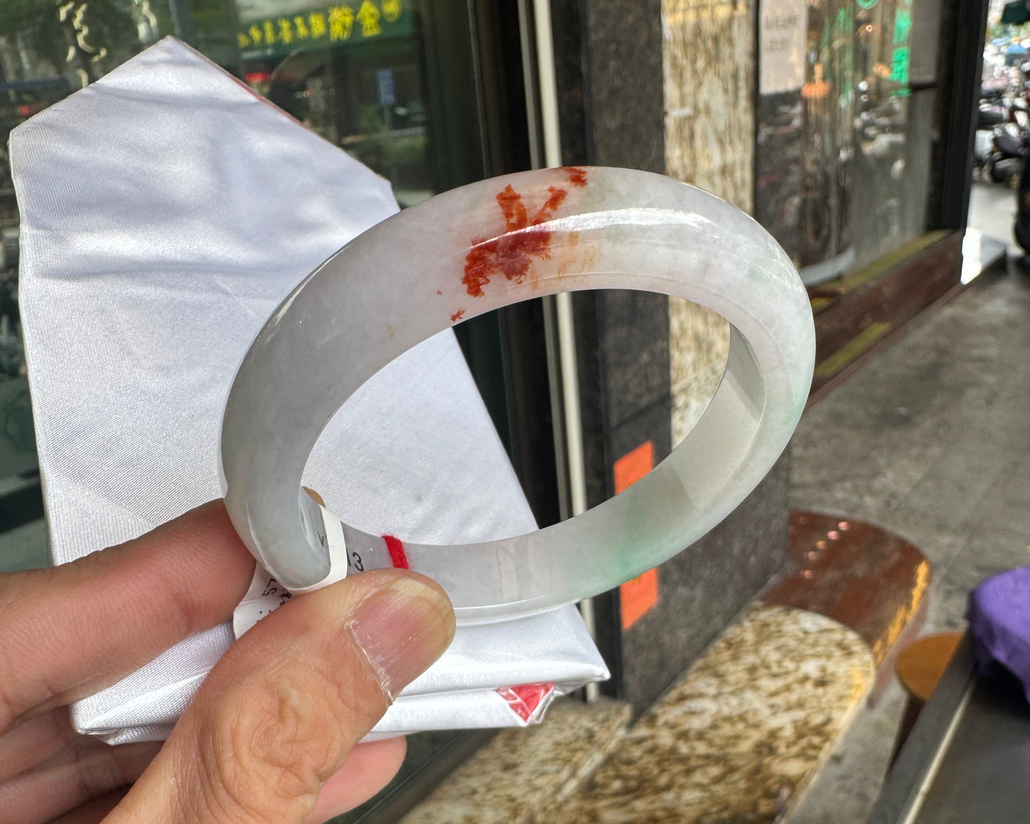 A white and green jade bangle with brownish yellow accents.