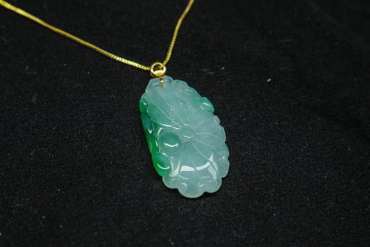 Green jade pendant on a gold chain against a black background