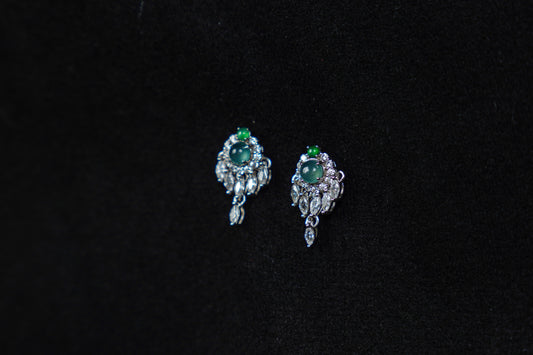 Pair of silver earrings with green gemstones on a black background