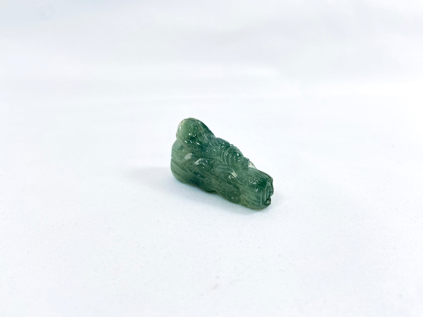 A transparent light green jadeite carved with a cicada on a tree trunk.