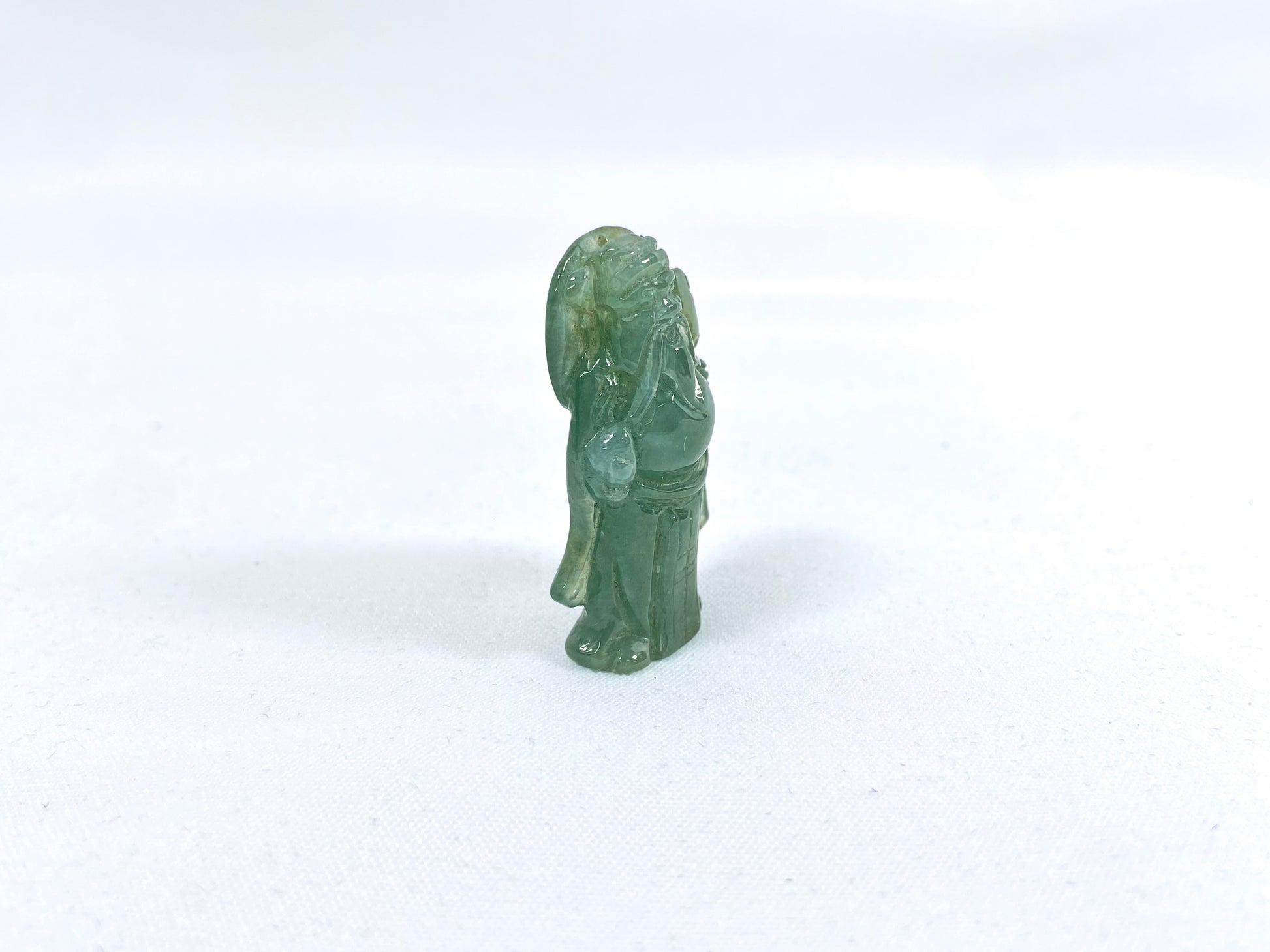 An icy light green jadeite loose stone carving of the God of Wealth.