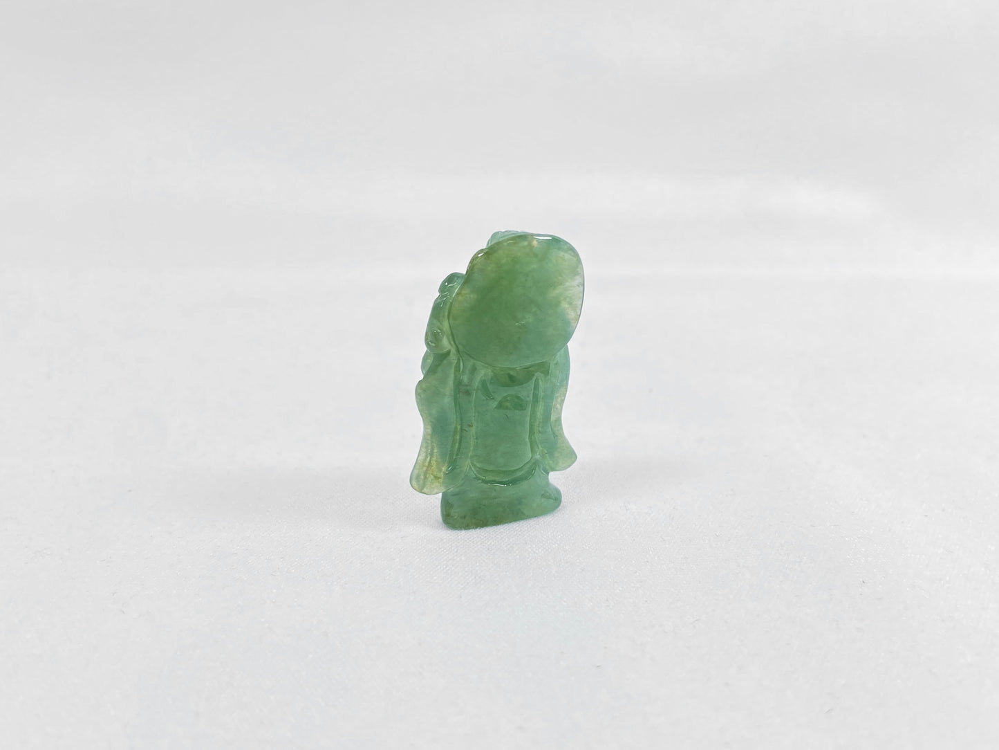 An icy light green jadeite loose stone carving of the God of Wealth.