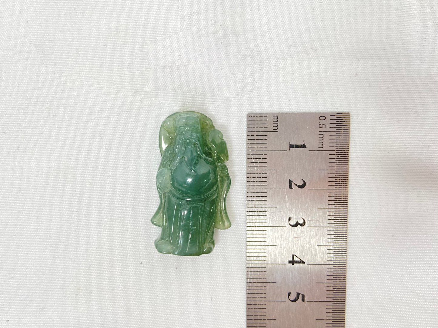 An icy light green jadeite carving of the God of Wealth.