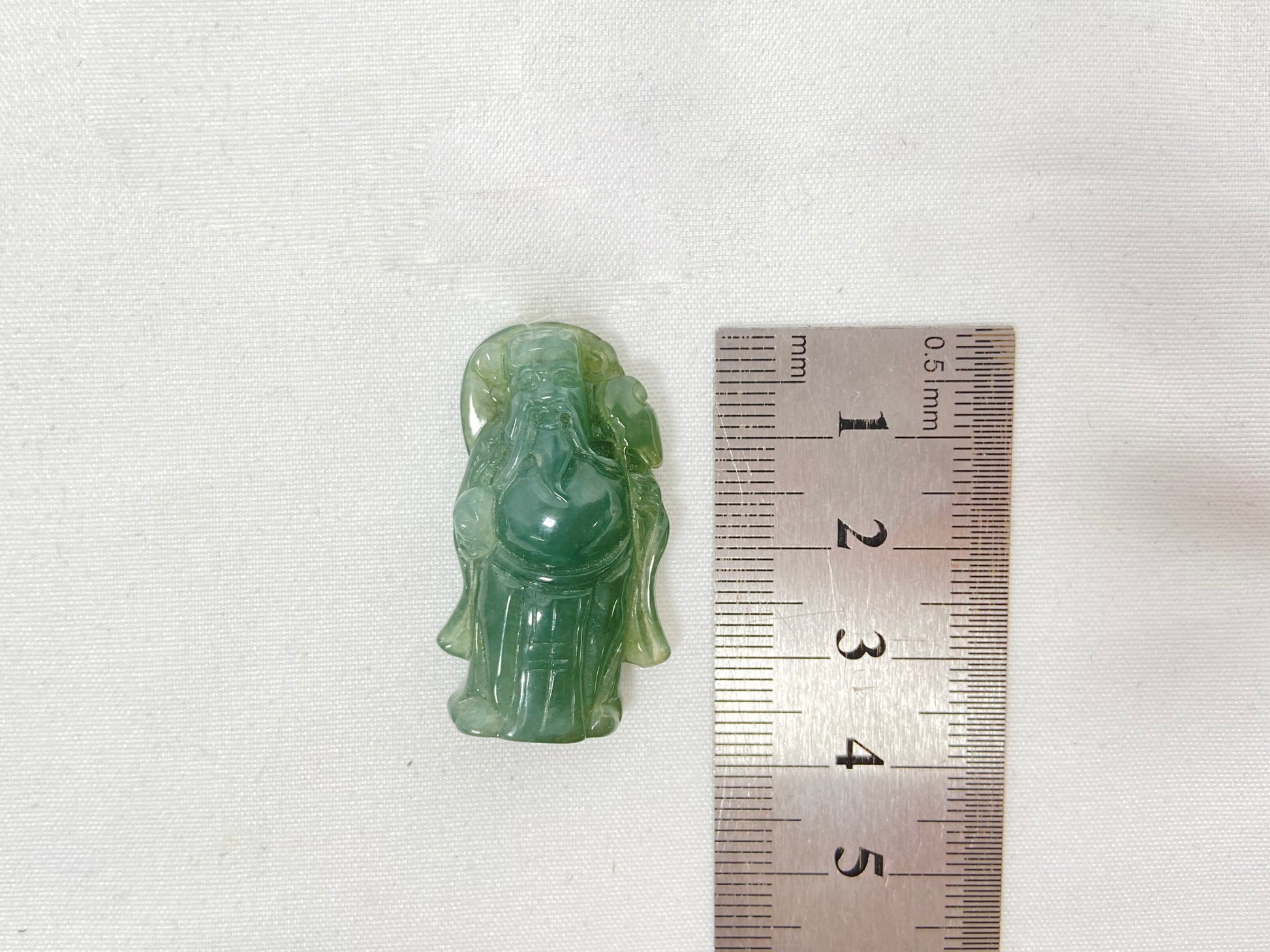 An icy light green jadeite carving of the God of Wealth.