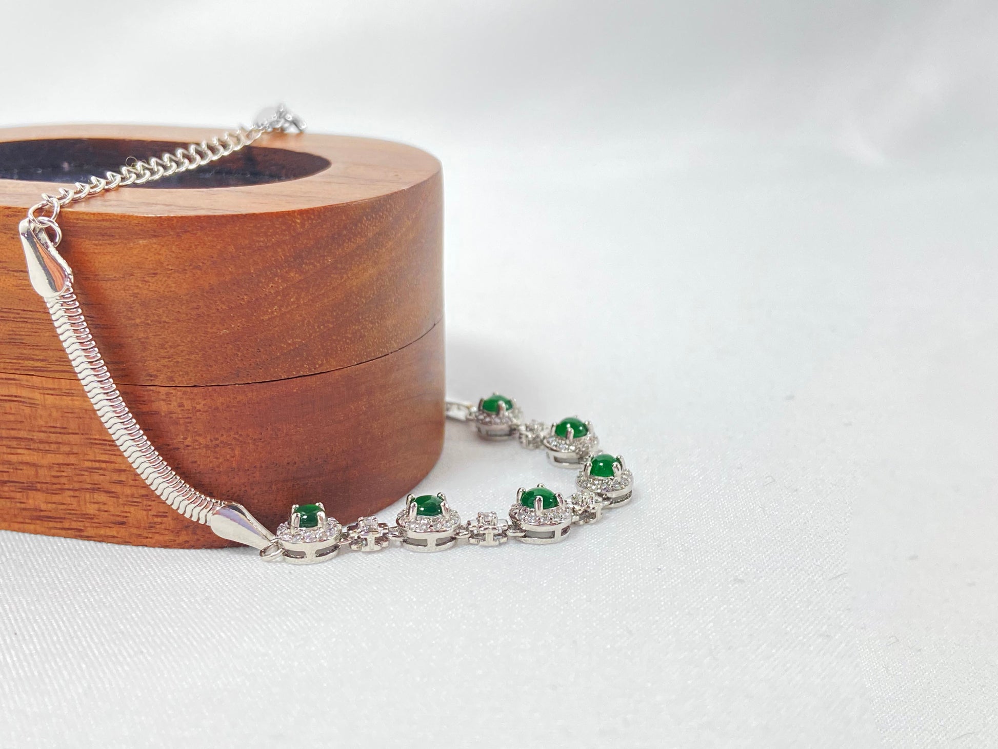 A bracelet featuring six vibrant green jade cabochons set in copper frames.