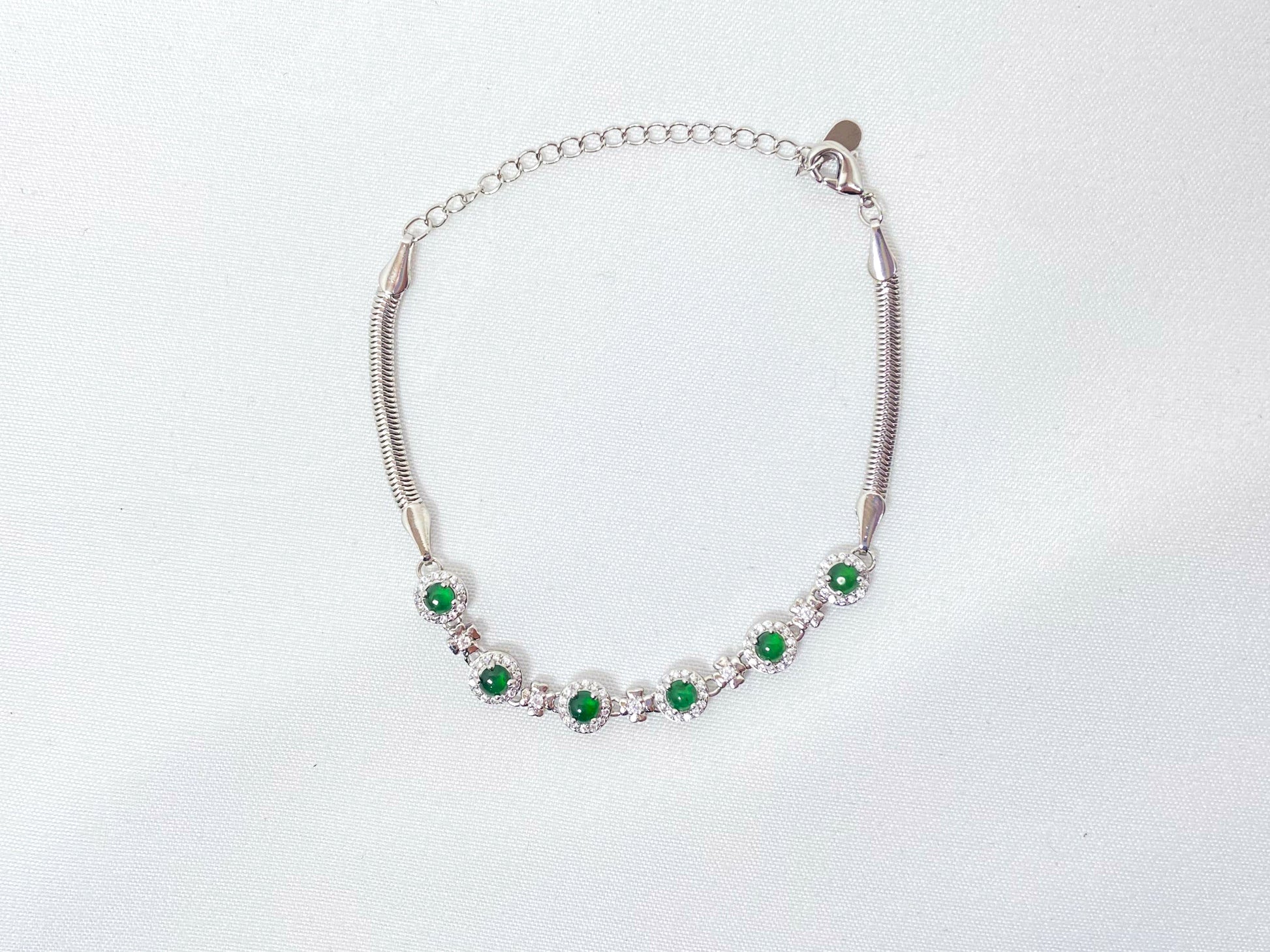A bracelet featuring six vibrant green jade cabochons set in copper frames.