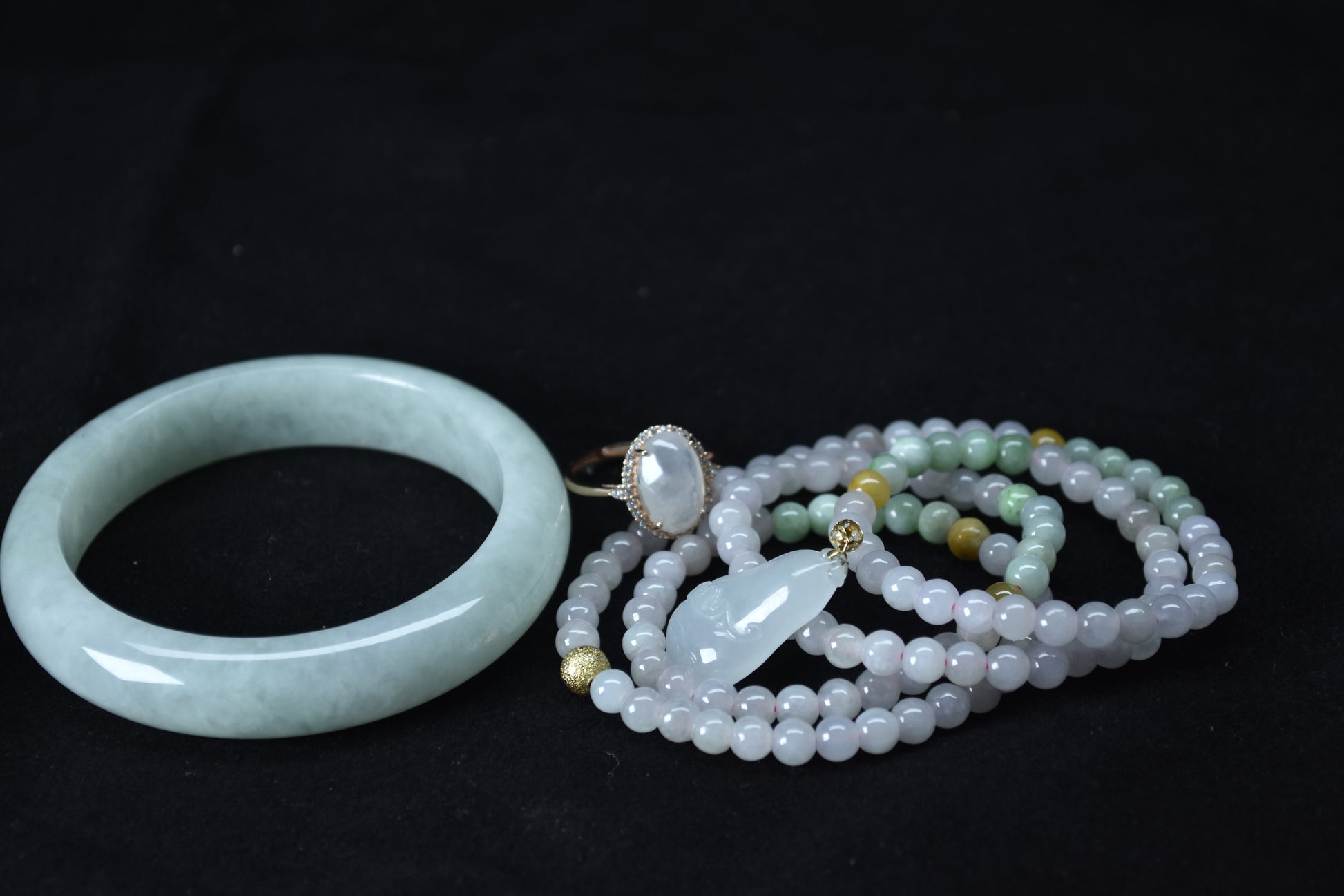 Jade bracelet, ring, and beaded necklace on a black background