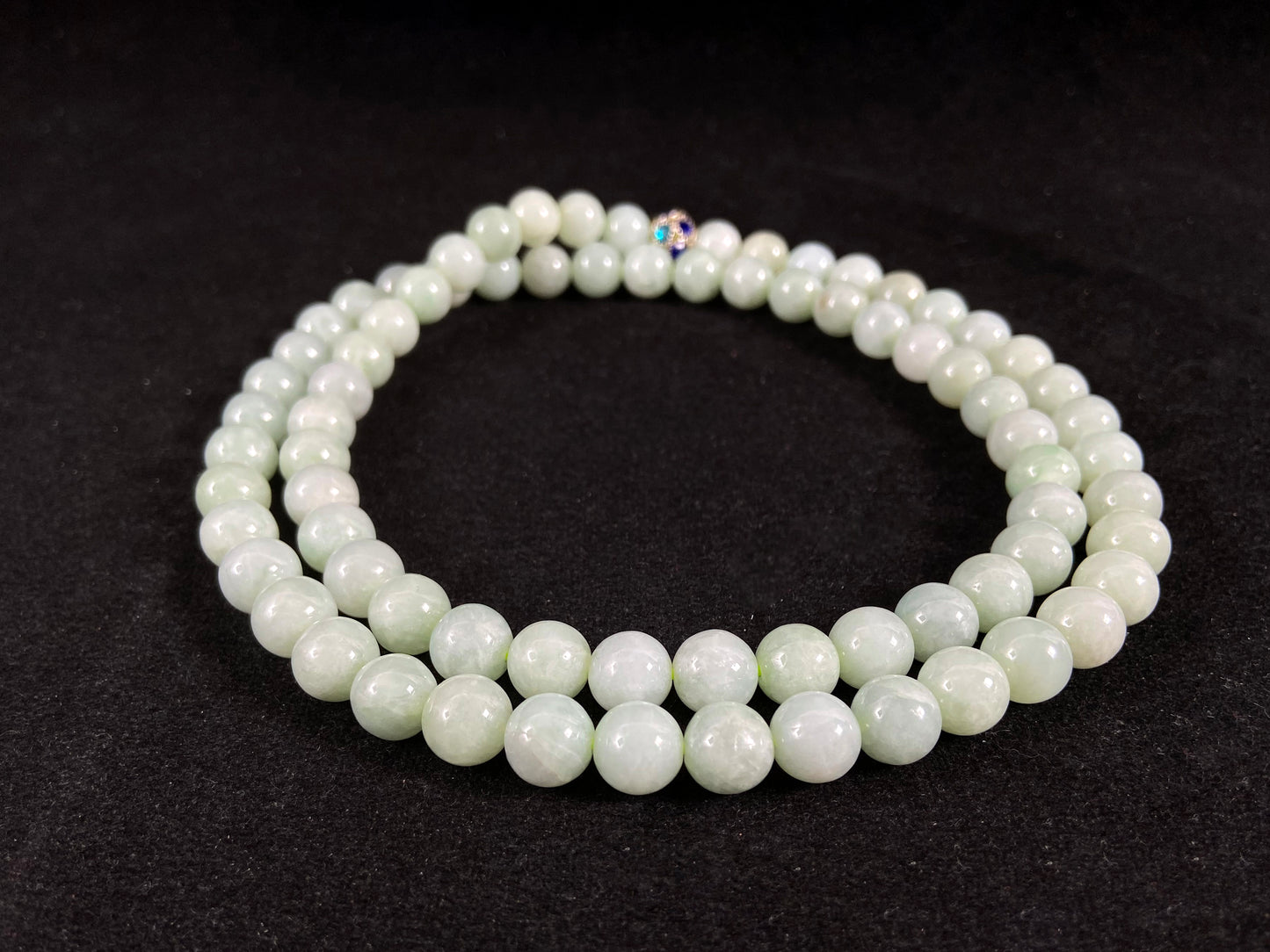 A jade bead strand in a pale whitish green hue.