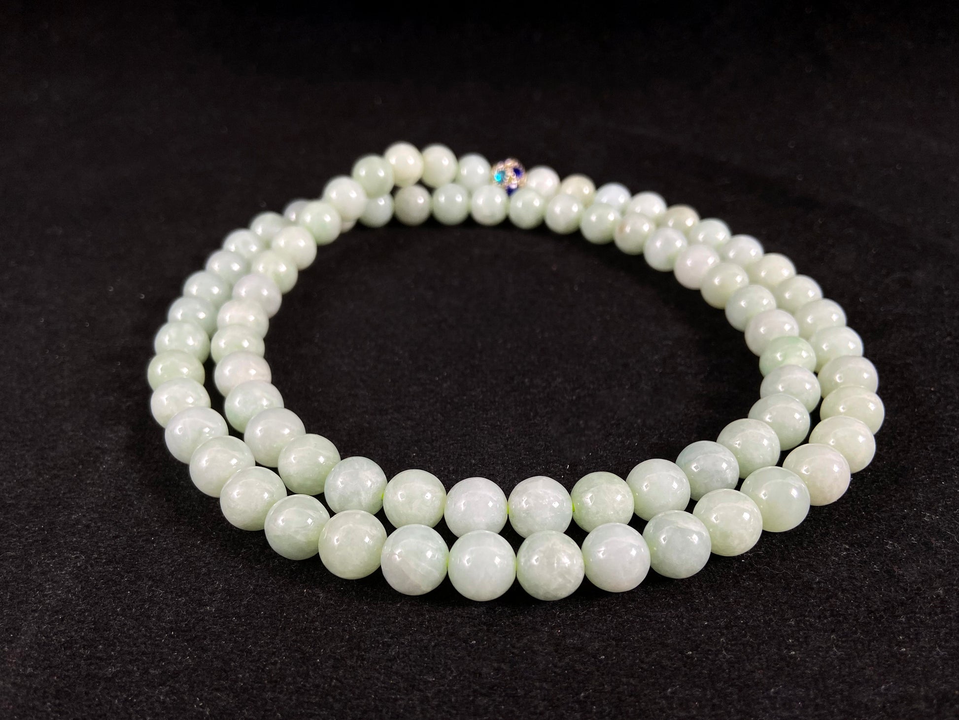 A jade bead strand in a pale whitish green hue.