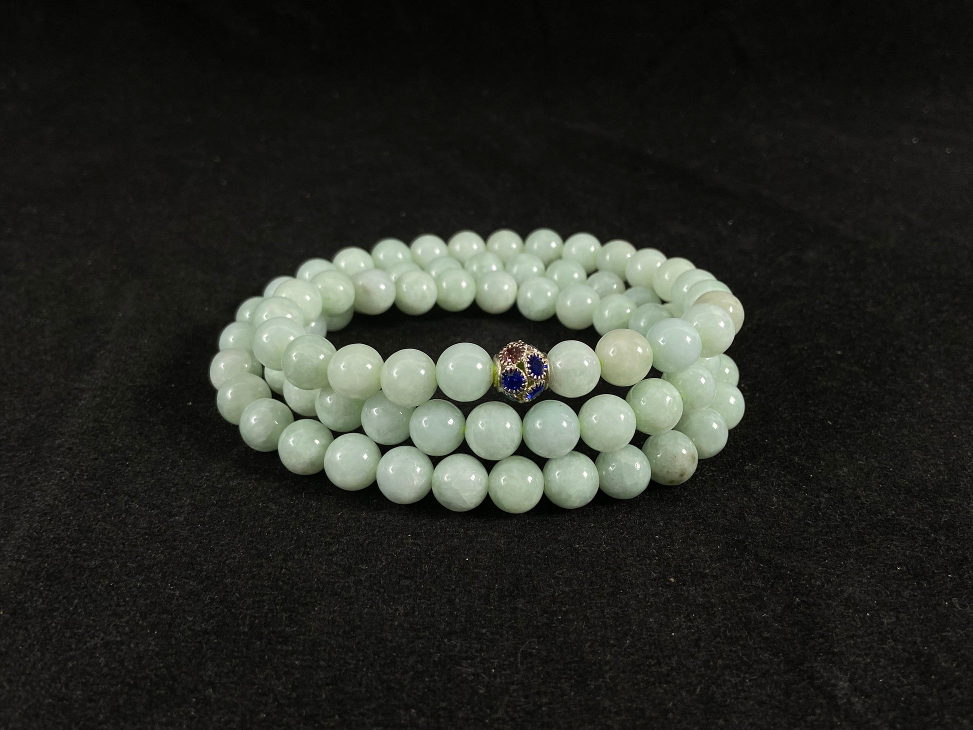 A jade bead strand in a pale whitish green hue.