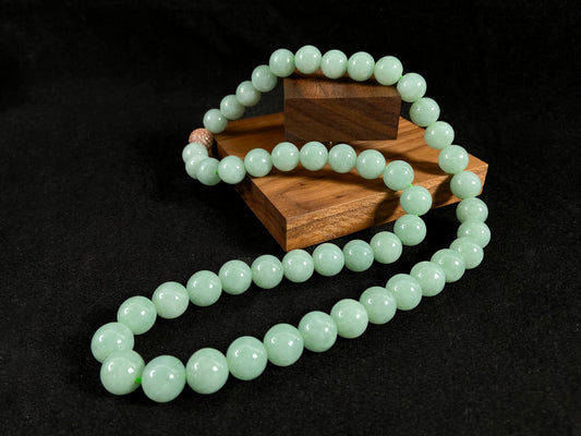 A jade bead strand featuring a gold mesh focal bead amid apple green beads.