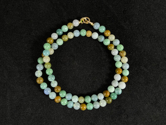 A jade bead strand featuring green, brown, pale yellow, white, and bluish purple beads.
